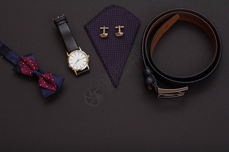 带金属扣的皮带黑色皮革表带的手表带袖扣的手帕和黑色背景的领结男士背景图片