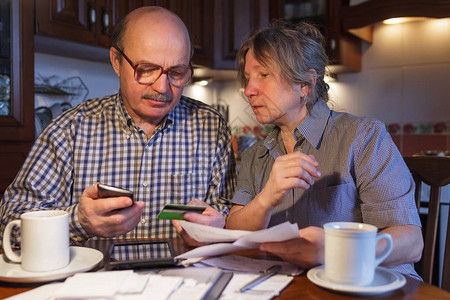 一对老年夫妇通过智能手机和银行卡使用电子支付他们害怕欺诈和不熟图片