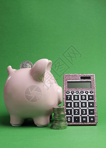 储蓄和购物出售概念与小猪银行一叠硬币和计算器在绿图片