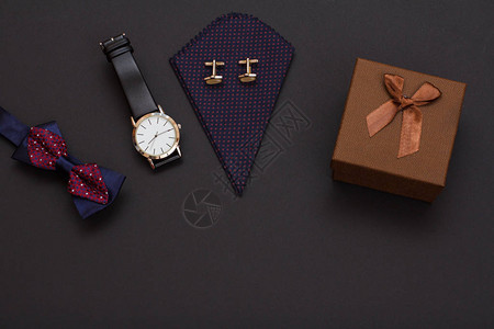 礼品盒带袖扣的手帕带黑色皮带的手表和黑色背景的领结男士背景图片