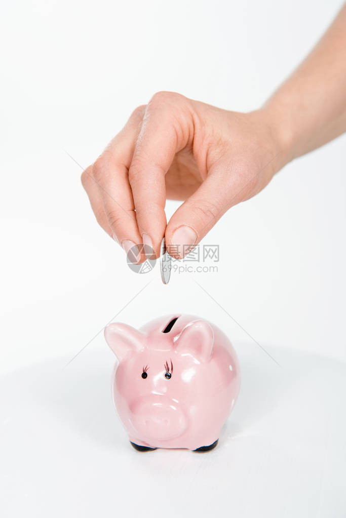 妇女将硬币投入白纸孤立的小猪银图片