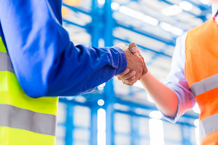 在工厂中握手的工人和工程师缔结合同协图片