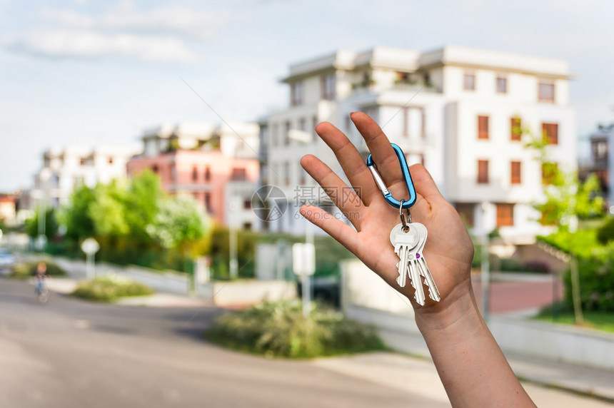 房地产代理商以模糊背景向新的地产所有人提供房屋钥匙的图片