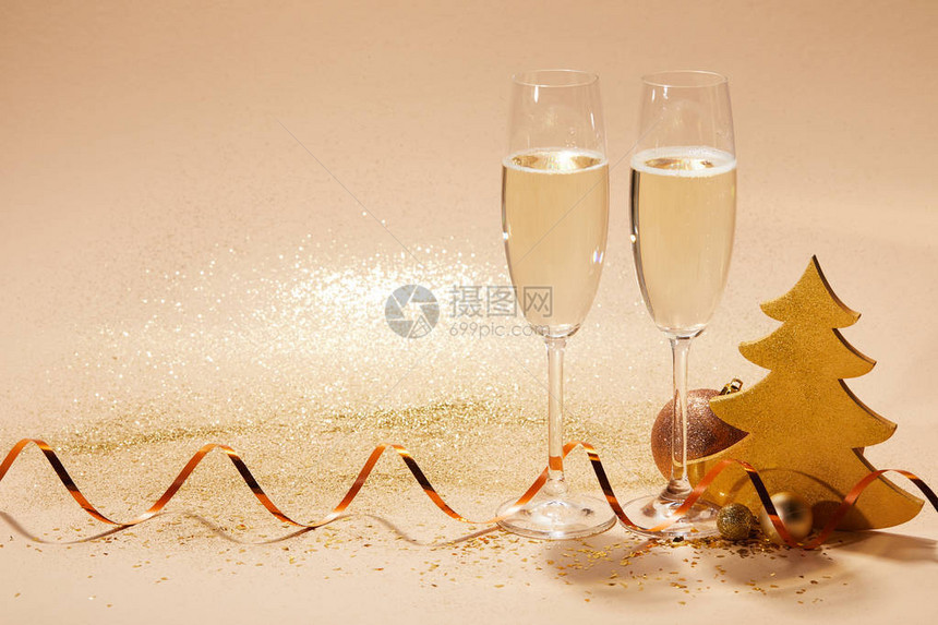 两杯香槟上面有卷状丝带和桌子上的闪光图片