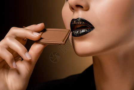 女人黑嘴唇和巧克力的特写图片