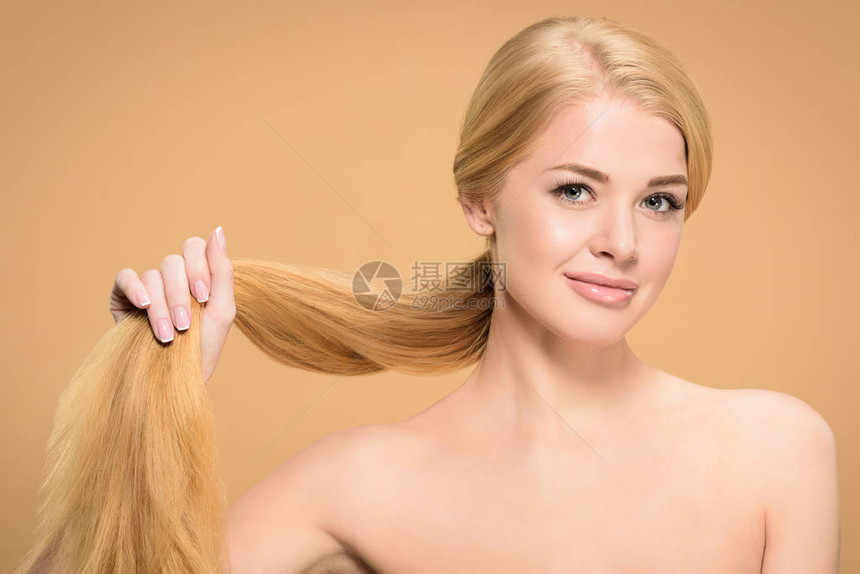 穿着长金发的长头发微笑着在米色上被图片