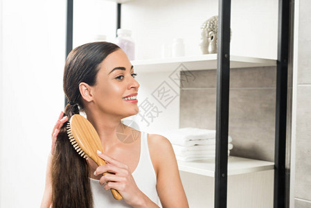 快乐的黑发女人在浴室里梳头图片