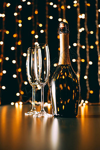 香槟酒瓶和玻璃杯加兰浅光背景图片