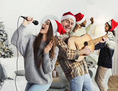 快乐的一对情侣弹吉他在家庭派对上唱圣诞图片