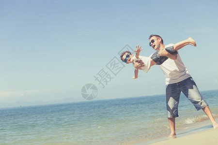父亲和儿子白天在沙滩上玩耍友善家庭的概念图片
