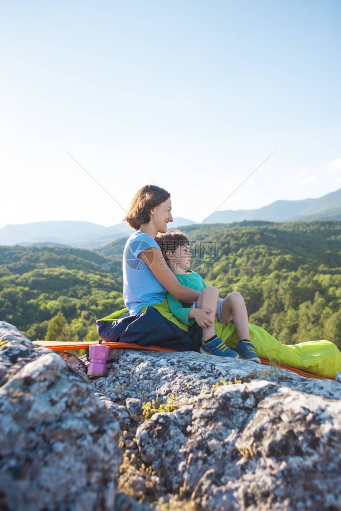 在山顶露营妈和孩子一起旅行一名妇女和她的儿子在攀登后休息睡袋里的女孩图片