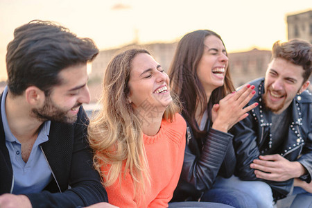 一群年轻朋友在暑假坐在户外长椅上玩笑话笑和聊天的乐趣图片