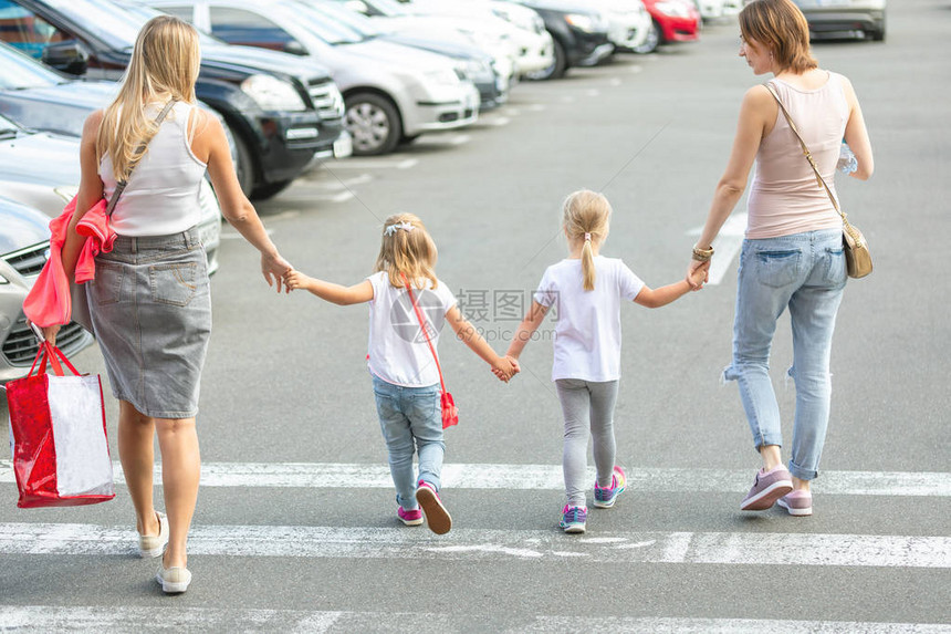 四个女朋友一起穿过人行横道两个年轻女子带着两个女儿在购物中心附近户外玩乐儿童和成图片
