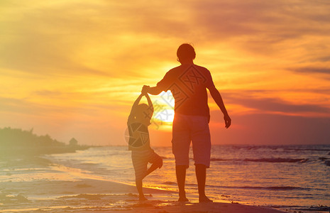 父亲和儿子在日落海边图片