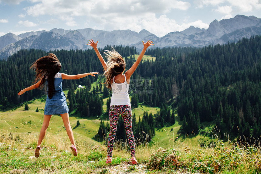 两个长头发女孩在山上快乐地跳跃令人兴奋的看图片