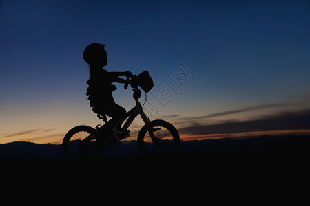 日落时骑自行车的小女孩背景图片