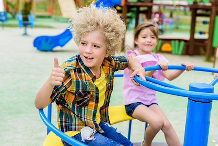 可爱的卷发男孩在操场骑着带小孩的旋转木马时图片