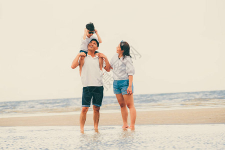 父亲母亲和儿子的幸福家庭暑假在热带沙图片
