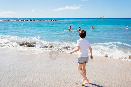 7岁快乐的男孩在海滩上走动图片