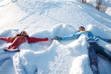 喜悦的男孩和女孩在冬季度假时躺在图片