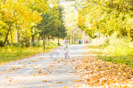 快乐的小女孩在秋天公园玩得开心图片