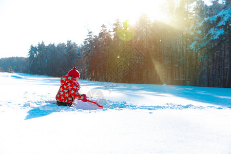 可爱的小女孩用铲子挖雪图片