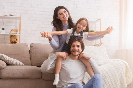 快乐的妈爸和他们可爱的女儿在家客厅摆姿势图片