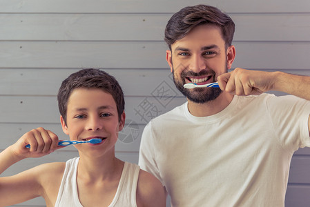英俊的年轻父亲和他的十几岁的儿子正在刷牙图片