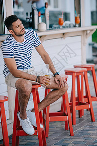 英俊的年轻人坐在沙滩酒吧时图片