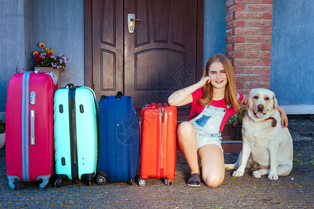 一个女孩和一只大拉布多犬靠近多色手提箱家庭准备暑假旅行全家人与一图片