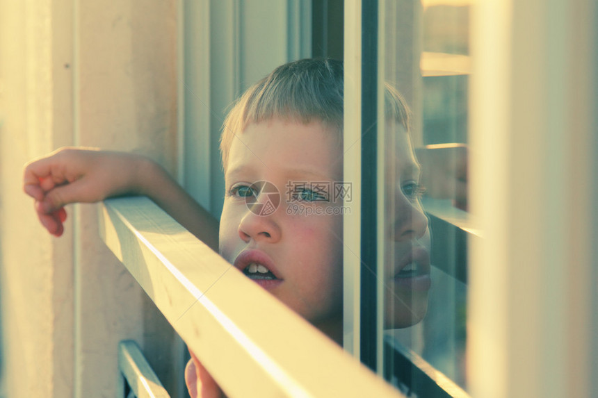 可爱的7岁男孩从窗图片