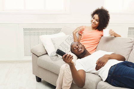 笑的非洲美国夫妇在家放松和看电视图片