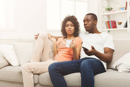 失望的非洲裔美国夫妇在家放松和看电视图片