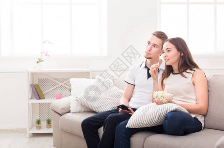 微笑的年轻夫妇在家放松和看电视图片