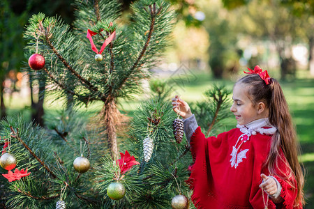 可爱的女孩在假期前在院子里装饰圣诞树圣诞快图片