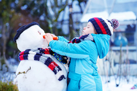 可爱的男孩在寒冷的日子里堆雪人图片