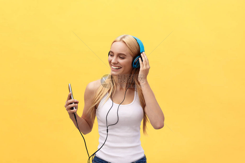 生活风格的肖像一个快乐的女人用耳机监听音乐在黄色图片