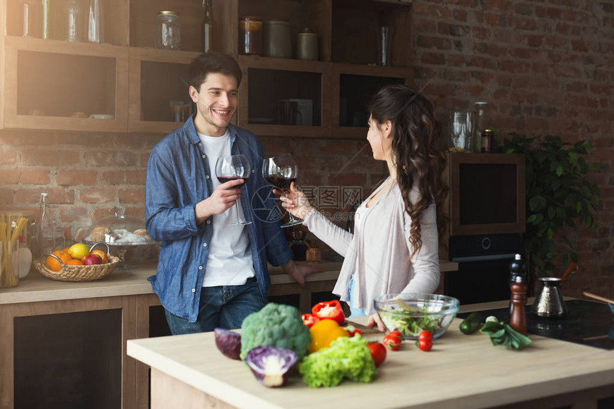 快乐的一对夫妇在家里的阁楼厨房一起做健康的食物和喝酒图片