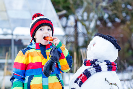 有趣的小孩在寒冷的日子里堆雪人图片