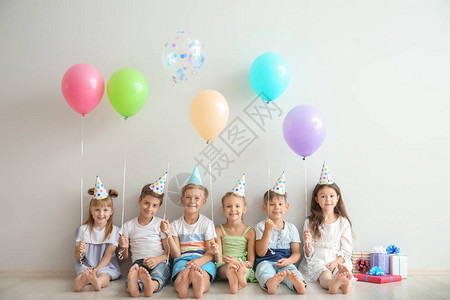 可爱的小孩戴着生日帽气球坐在靠近图片