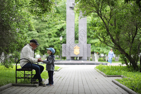 方聪一爷和她的孙子在一个春天的公园里散步孙子和祖父在散步爷正在和一背景