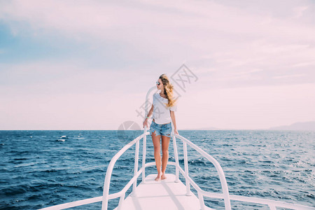 美丽的女站在游艇的鼻子上在阳图片