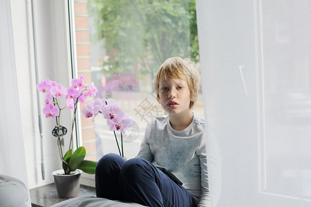 8岁男孩坐在窗户旁边玩平板电图片
