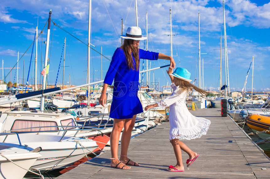 年轻妈和小漂亮女孩在港口享受阳光图片