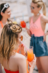 年轻女子在沙滩上与女朋友共饮夏鸡尾酒图片