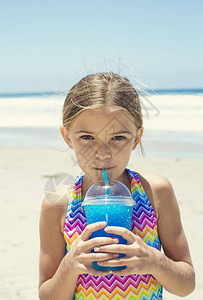 在沙滩度假的热暑假期间享受蓝冰饮料的可图片