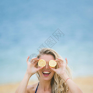 有魅力的年轻女人用柠檬片遮住眼睛沙滩图片