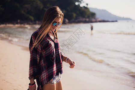 夏季阳光明媚的生活方式时尚肖像的年轻时尚髦女人走在沙滩上图片