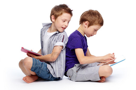 男孩们使用高科技数字平板背靠坐着图片