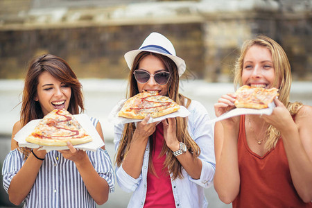三个年轻女人在购物后吃披萨图片